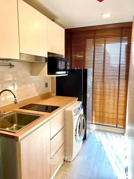 Modern kitchen with washing machine and sleek wooden cabinets