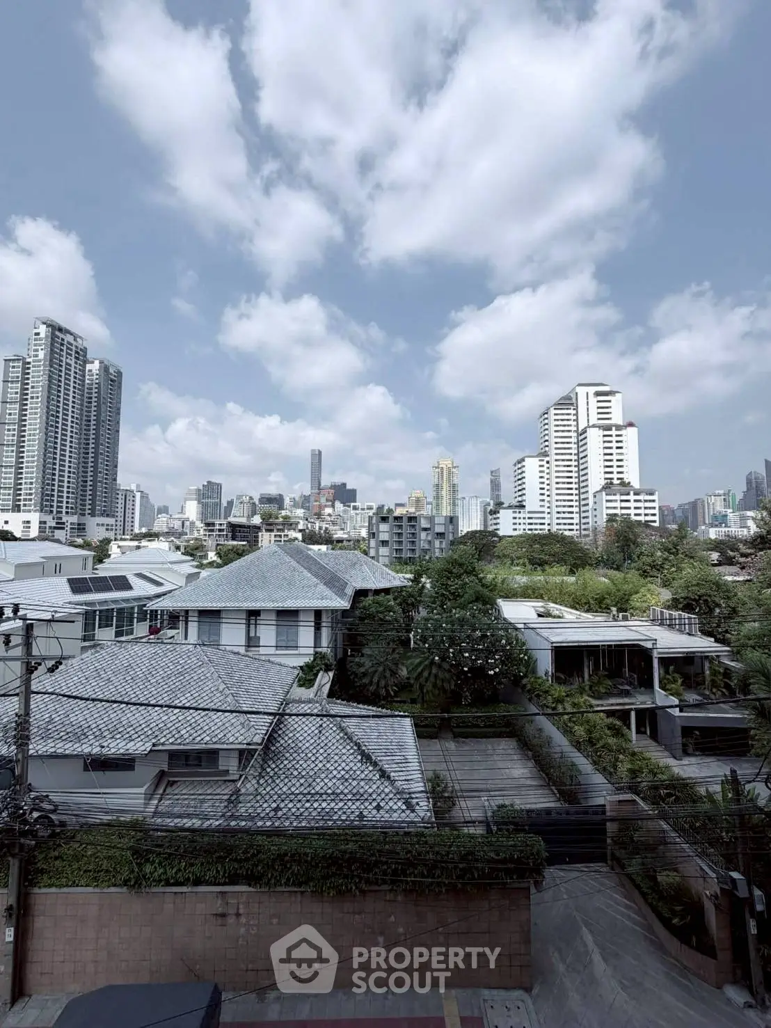 Stunning cityscape view showcasing modern skyscrapers and residential rooftops under a vibrant blue sky.