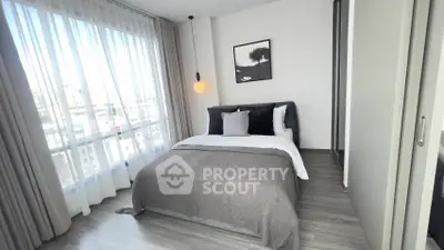 Modern bedroom with large window and stylish decor in urban apartment.