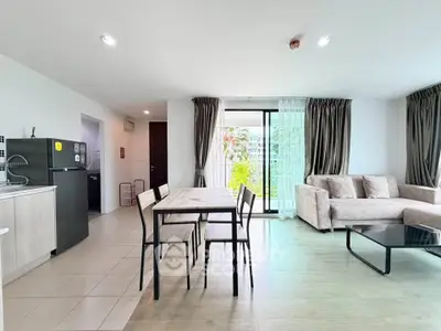 Spacious modern living room with open kitchen and balcony view, featuring elegant decor and natural light.