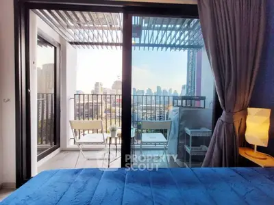 Modern bedroom with balcony offering stunning city view and cozy seating area.