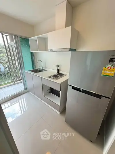 Modern compact kitchen with sleek appliances and balcony view, perfect for urban living.