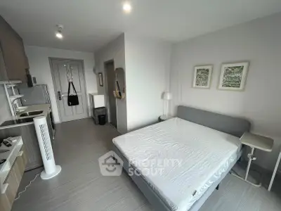 Modern studio apartment with sleek kitchen and cozy bed, perfect for urban living.