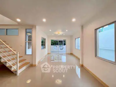 Spacious modern living room with large windows and staircase, ideal for family gatherings.
