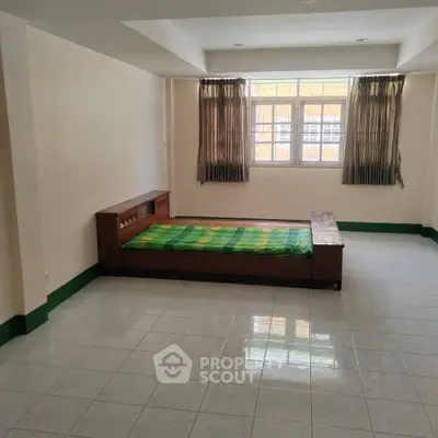 Spacious bedroom with natural light and minimalist design, featuring a single bed and tiled flooring.