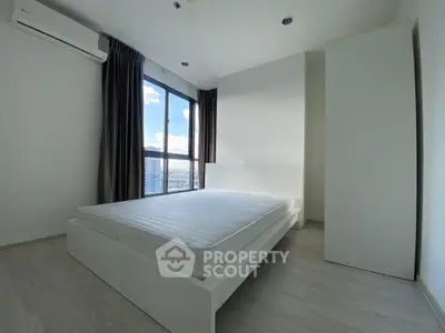 Modern minimalist bedroom with large window and city view, featuring sleek white furniture and natural light.