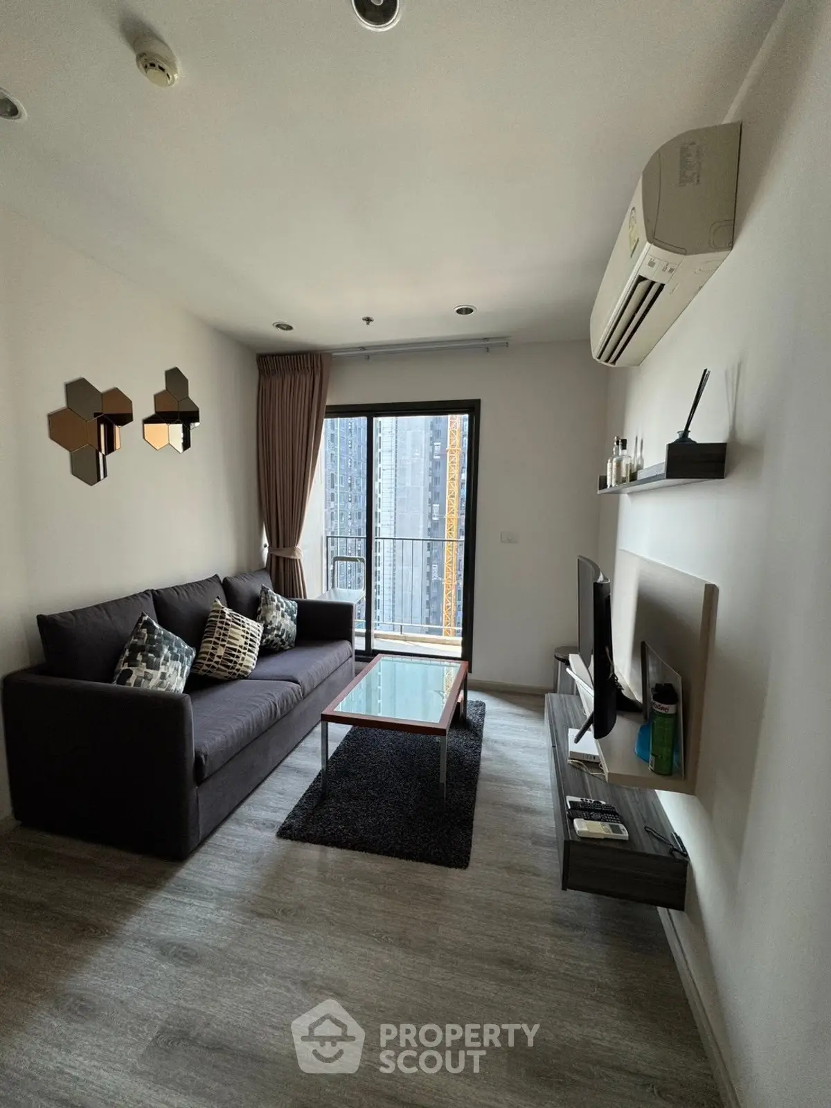 Modern living room with sleek design, featuring a comfortable sofa, stylish decor, and a balcony with city views.