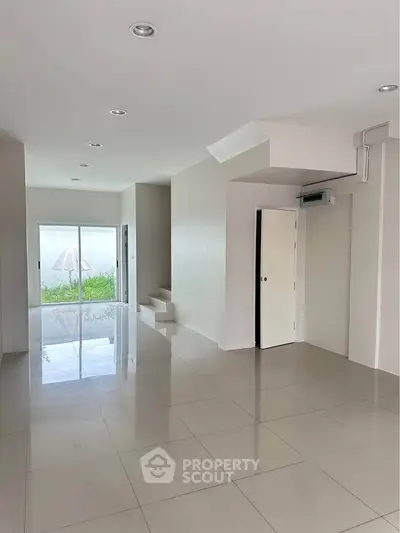 Spacious modern interior with glossy tile flooring and garden view, perfect for contemporary living.