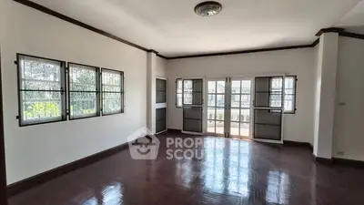 Spacious living room with large windows and polished wooden floors