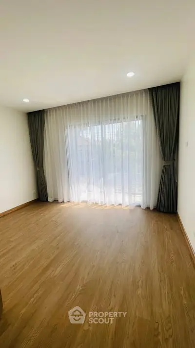 Spacious empty room with large window and elegant curtains, perfect for customization.
