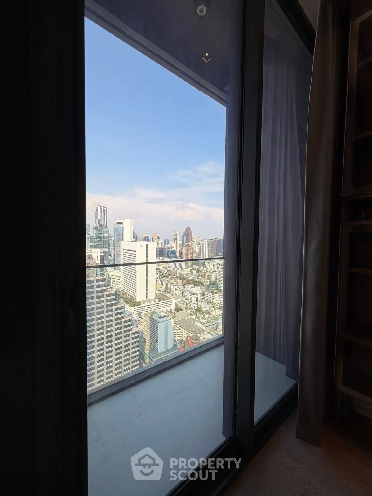 Stunning cityscape view from high-rise apartment balcony with glass doors.
