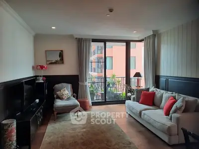 Charming living room with cozy seating and large windows opening to a balcony view.