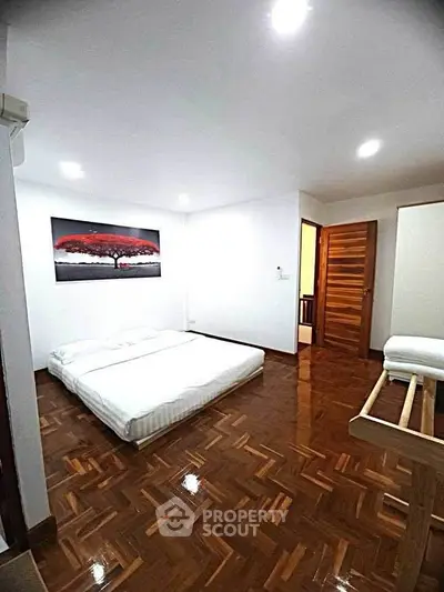 Spacious bedroom with wooden flooring and modern decor in a stylish apartment.