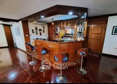 Luxurious home bar with elegant wooden finish and stylish bar stools in a spacious living area.
