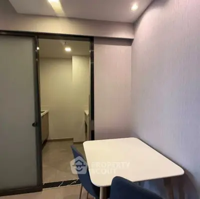Modern dining area with minimalist table and chairs, adjacent to a sleek bathroom entrance.