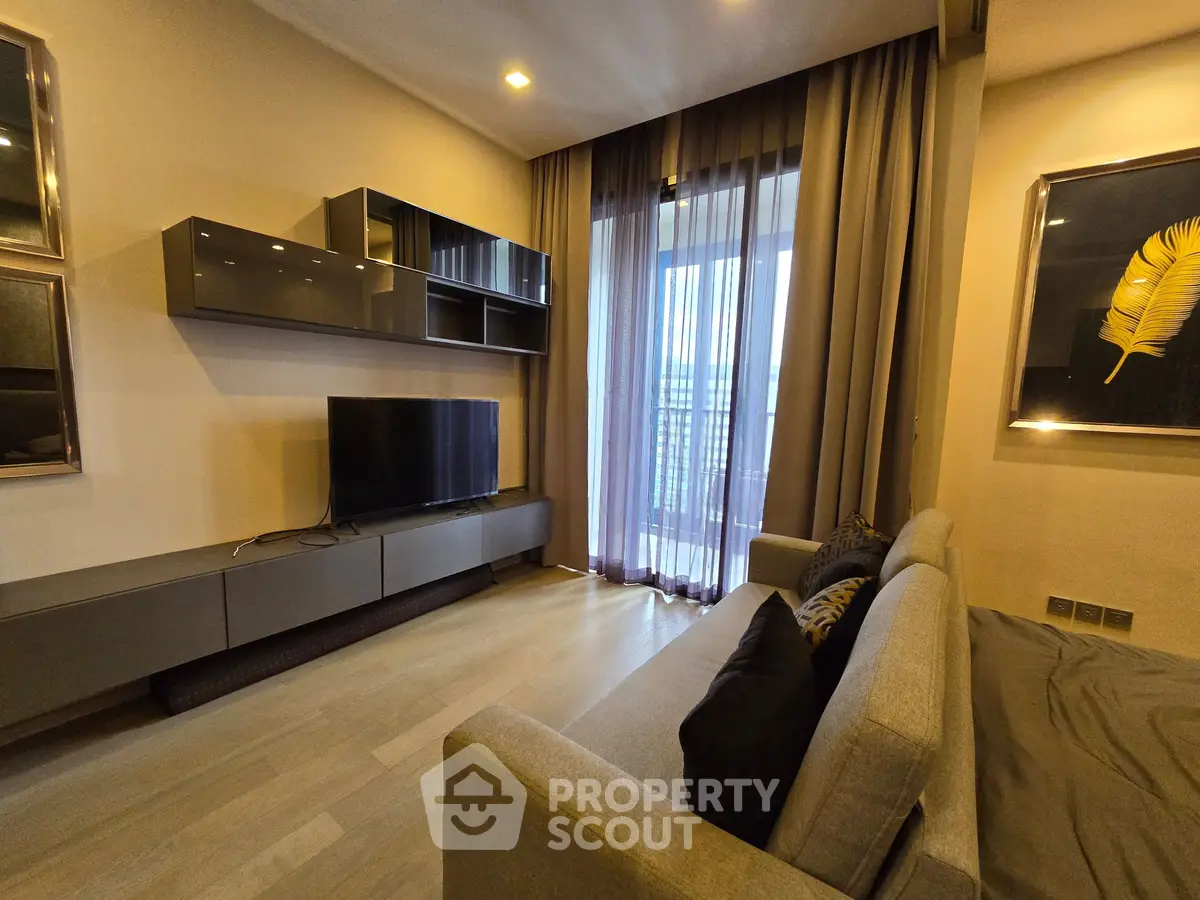 Modern living room with sleek furniture and large window offering natural light.