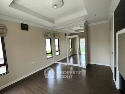 Spacious room with large windows and mirrored wall, perfect for versatile living space.