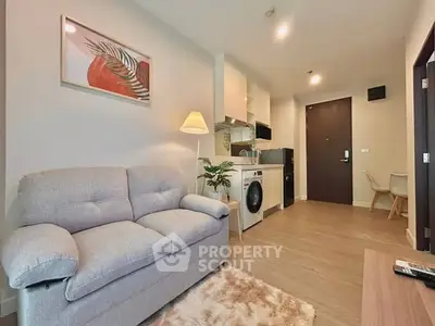 Modern living room with cozy sofa and integrated kitchen appliances in a stylish apartment.