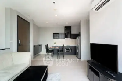 Modern open-plan living room with sleek kitchen and dining area, featuring contemporary furniture and appliances.