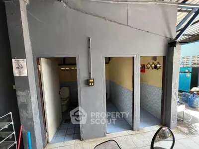 Simple outdoor restroom area with basic amenities and tiled flooring.