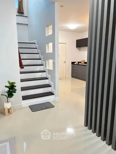 Modern interior with sleek staircase and open kitchen layout, perfect for contemporary living.