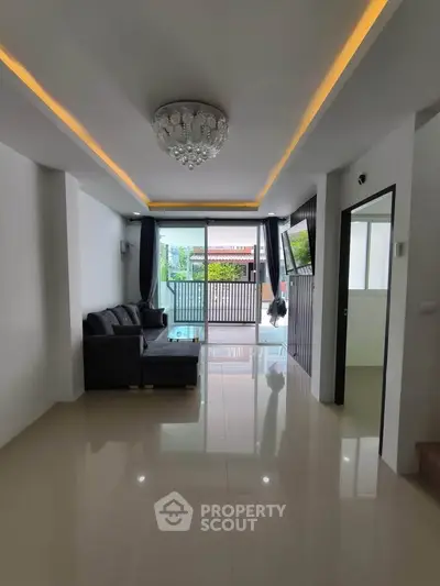 Spacious modern living room with elegant chandelier and large windows.
