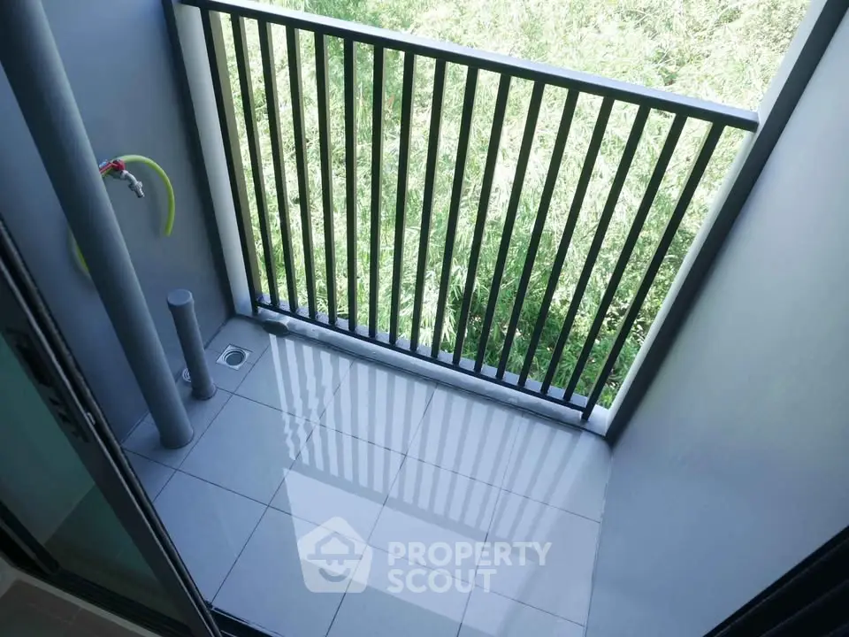Compact balcony with sleek railing and lush green view, perfect for urban living.