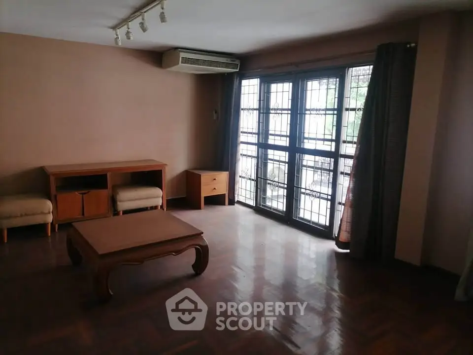 Spacious living room with parquet flooring and large windows for natural light.