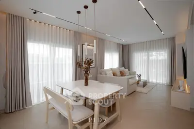 Elegant modern living room with dining area, featuring stylish decor and natural light through large windows.