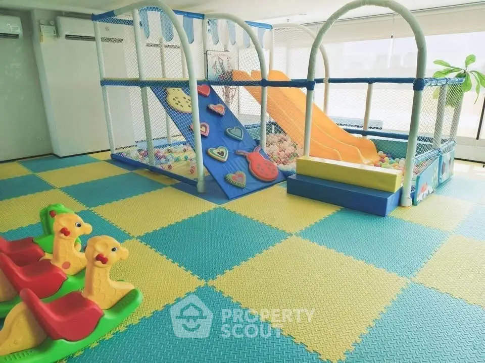 Bright and colorful indoor play area with slides and soft flooring in a family-friendly building.