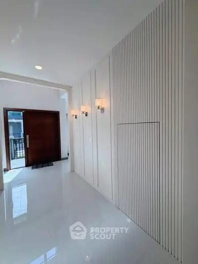 Elegant modern entrance with sleek white paneling and stylish lighting fixtures.