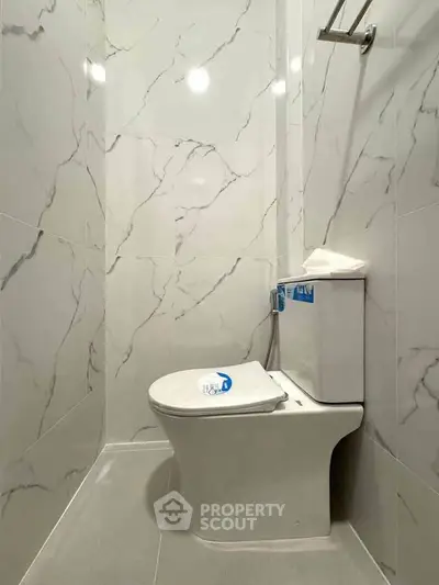 Modern bathroom with sleek marble walls and contemporary toilet design.