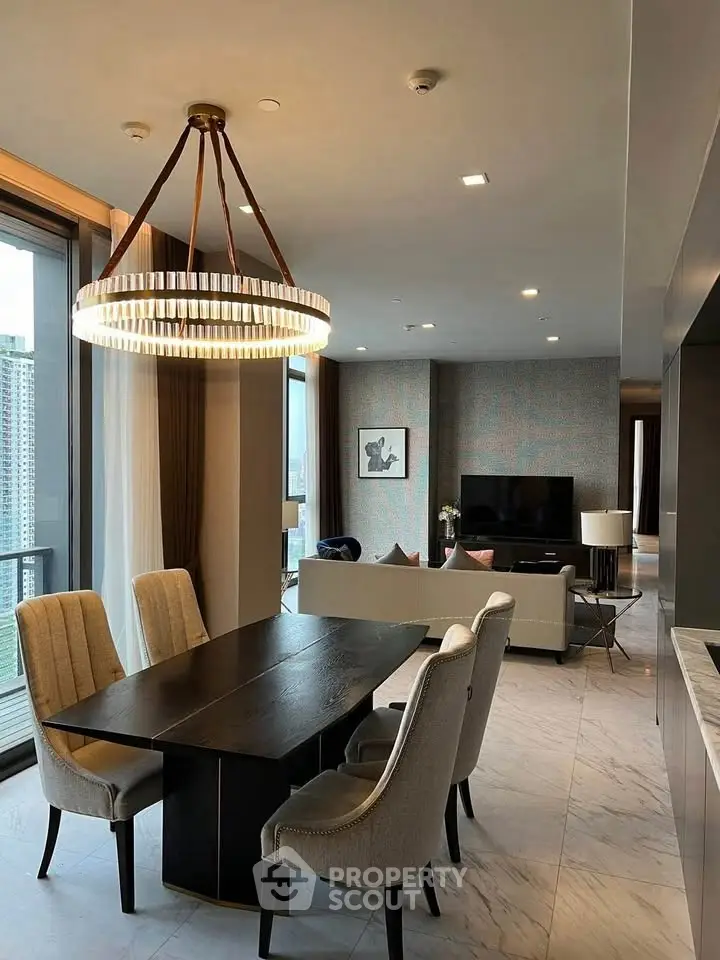 Luxurious open-plan living and dining area with elegant chandelier and city view.
