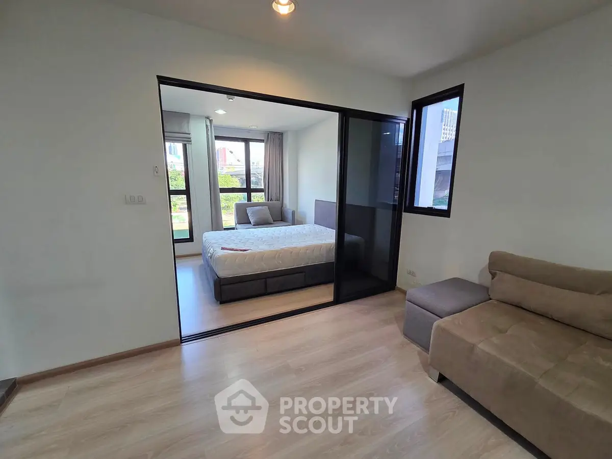 Modern apartment with spacious bedroom and cozy living area, featuring large windows and sleek flooring.