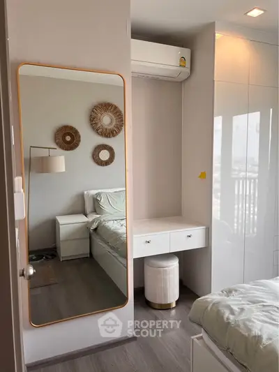 Modern bedroom with stylish decor and built-in storage, featuring a large mirror and air conditioning.