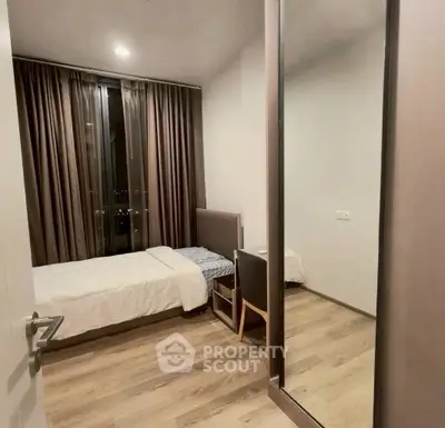 Modern bedroom with large mirror and city view, featuring sleek wooden flooring and elegant curtains.