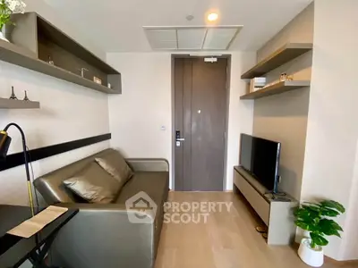 Modern living room with sleek sofa, TV, and stylish shelves in a compact space.