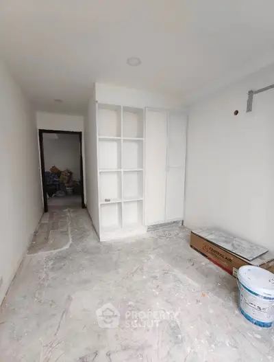 Spacious under-construction room with built-in shelves and closet, ideal for customization.