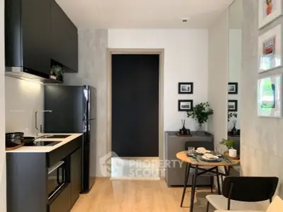 Modern kitchen with sleek black appliances and cozy dining area in stylish apartment.