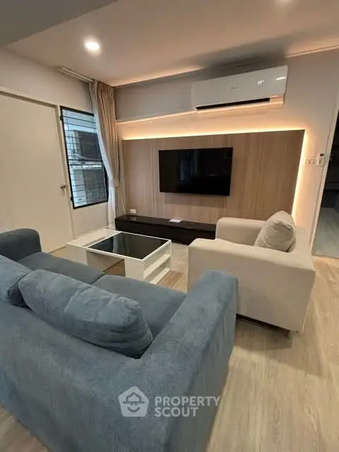 Modern living room with stylish furniture and wall-mounted TV, featuring cozy seating and elegant lighting.