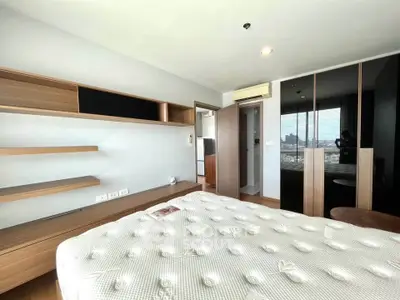 Modern bedroom with sleek wooden shelves and large mirrored wardrobe in a bright apartment.