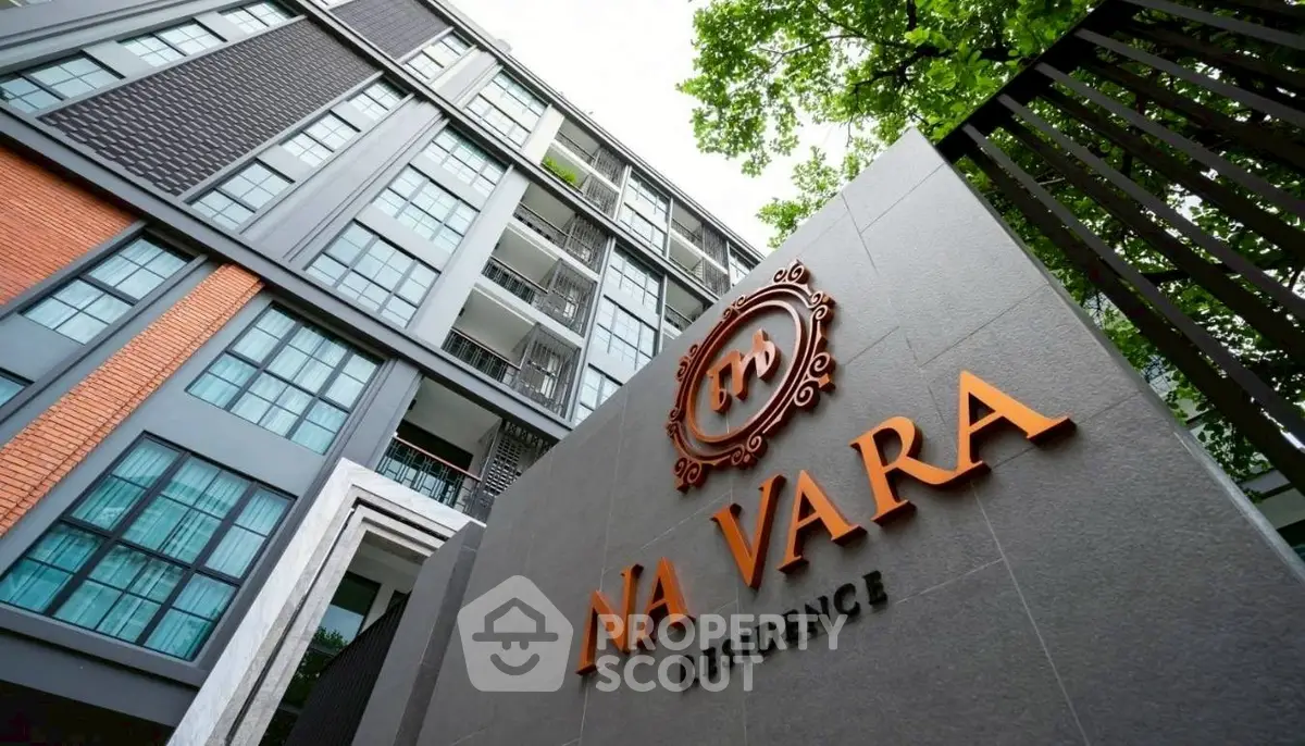 Modern building exterior with Na Vara Residence signage, showcasing contemporary architecture and lush greenery.