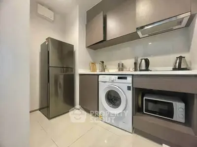 Modern kitchen with sleek appliances including fridge, washing machine, and microwave in stylish cabinetry.