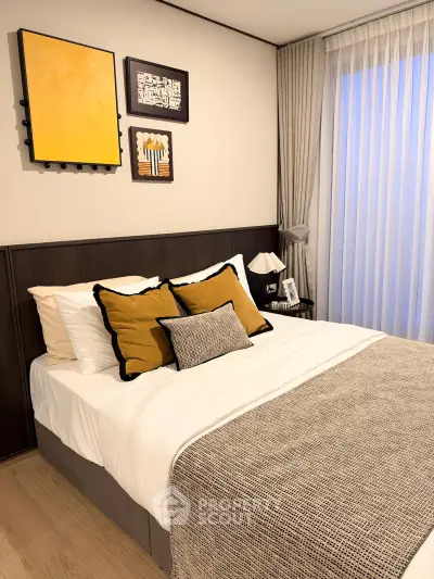 Cozy bedroom with stylish decor and natural light, featuring a comfortable bed and elegant wall art.
