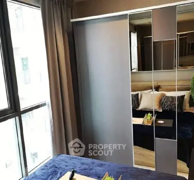 Modern bedroom with mirrored wardrobe and large window for natural light.