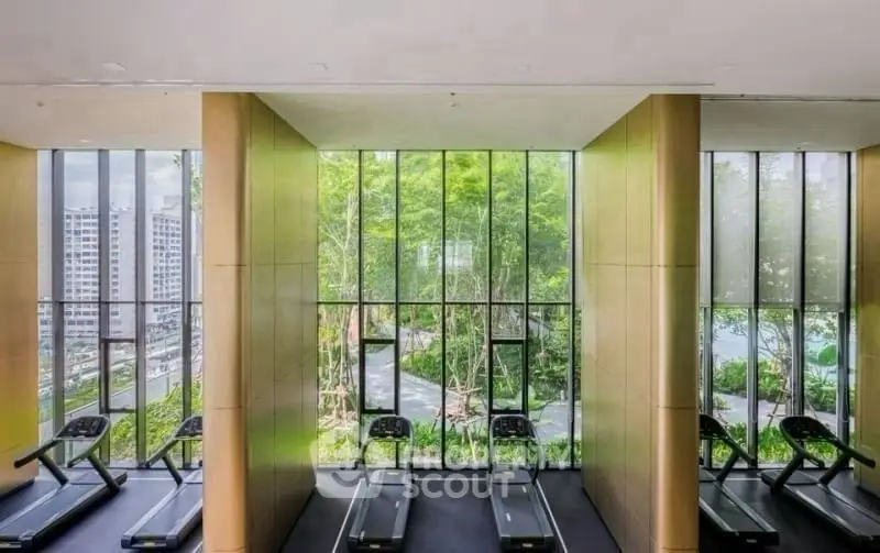 Modern gym with large windows offering lush garden views and state-of-the-art treadmills.