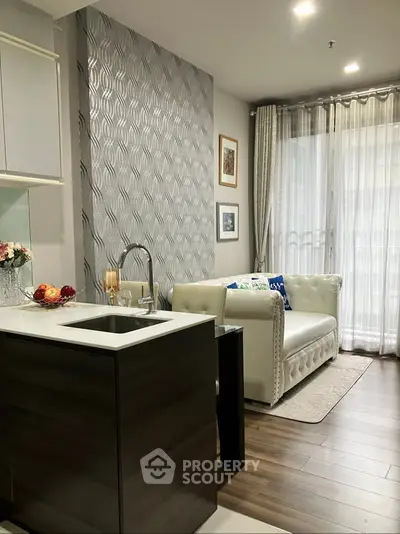 Modern living room with elegant decor and open kitchen layout, featuring stylish furniture and natural light.