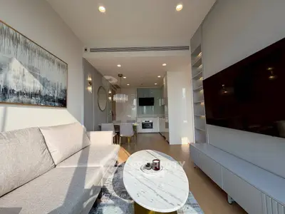 Modern living room with open kitchen, stylish decor, and natural light.