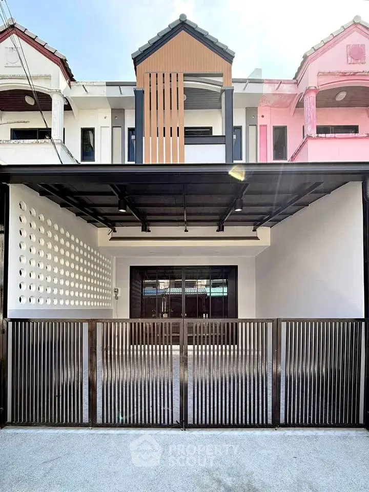 Modern townhouse exterior with sleek metal gate and unique facade design.