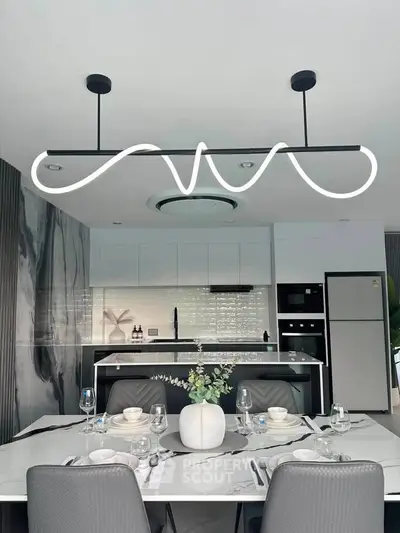 Modern kitchen with sleek design, featuring a stylish dining area and contemporary lighting.